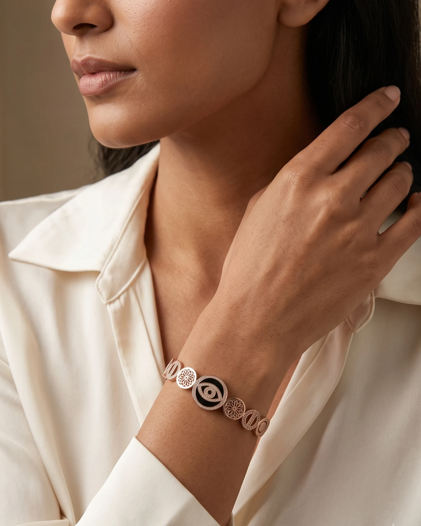Close view of a hand wearing a Krasna rose-gold charm bangle — visualised campaign imagery